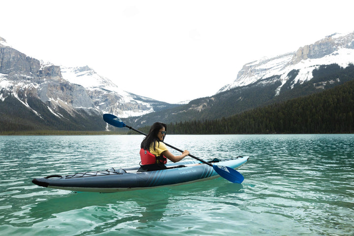 Chelan 120 kayak on a clear lake with snow-capped mountains in view.