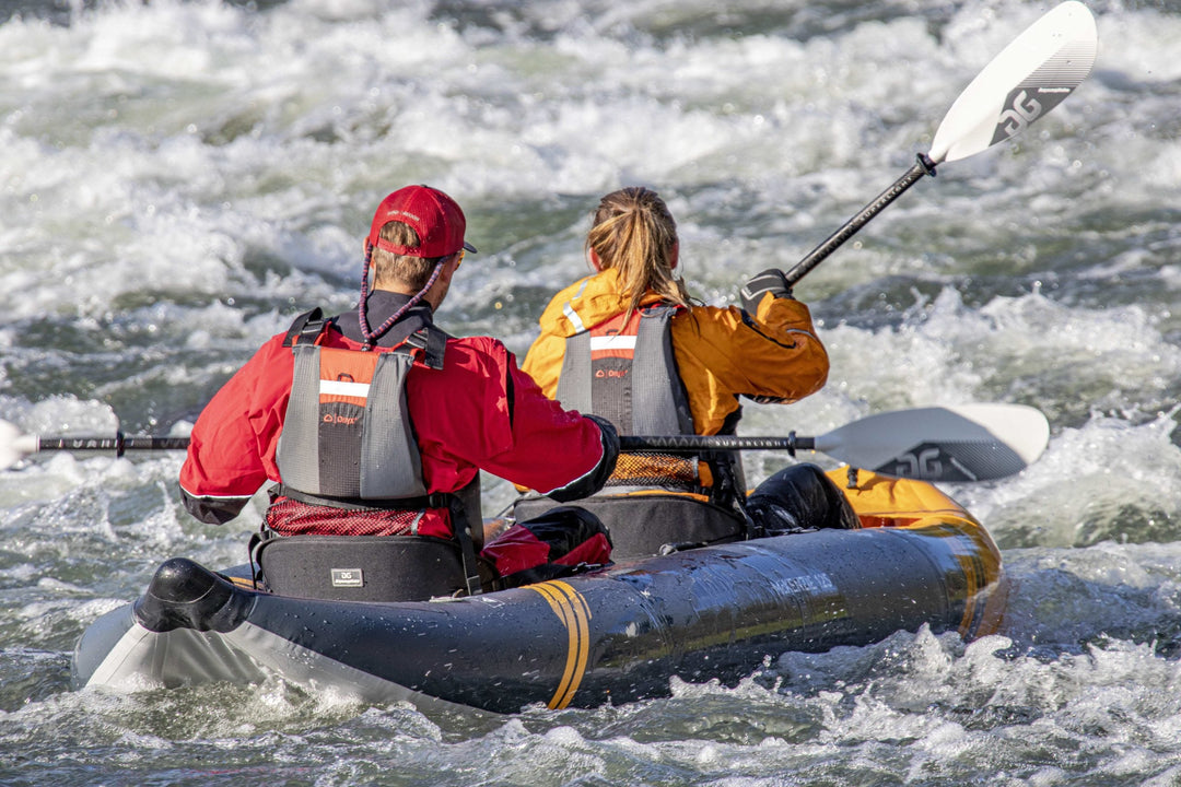 Two people paddling through whitewater rapids in a tandem kayak.