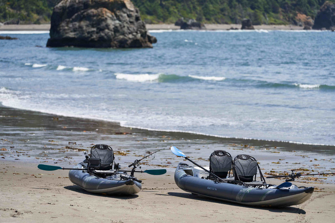 Two kayaks on a sandy beach with a rocky formation and ocean in the background.