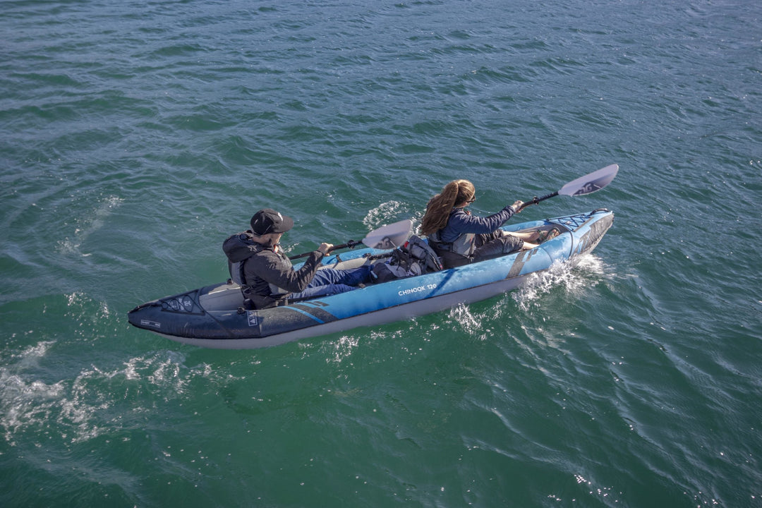 A man and woman kayaking through clear water, paddling in sync.
