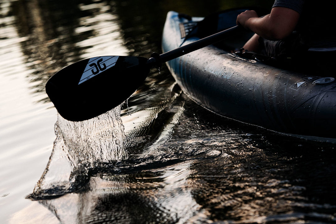 Close-up of a paddle dipped into the water with droplets splashing from it.