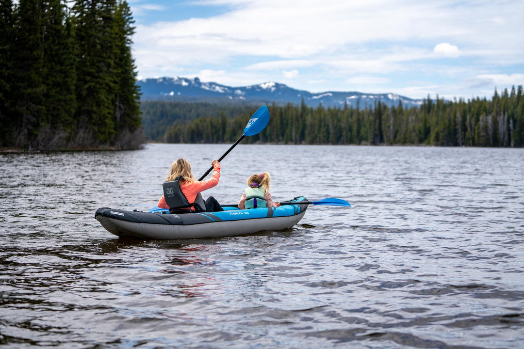 Woman and child in an inflatable kayak on a lake with a scenic backgroud.
