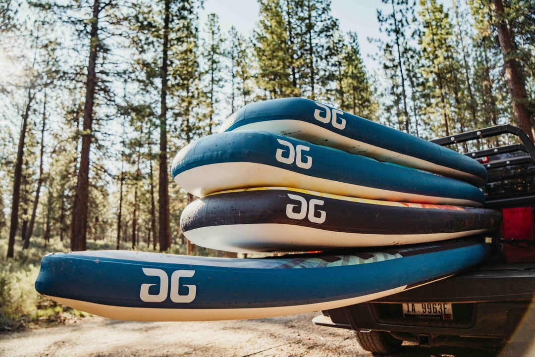 Several inflatable paddleboards stacked on a vehicle in a forested area.