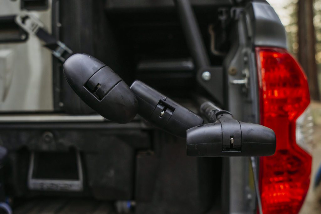 Black spare tire carrier arm on the back of a vehicle near a red tail light.