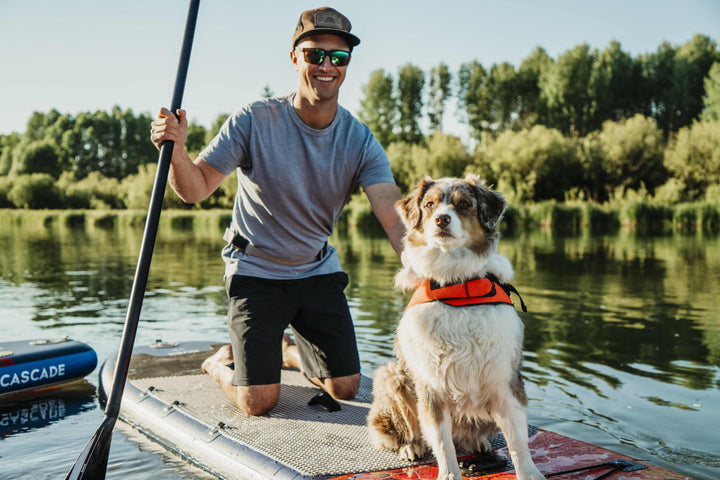 Man paddleboarding with a dog in a life jacket on a stable Kush 11 Paddleboard.