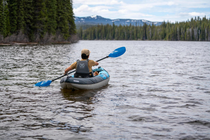Recreational paddling in a Chinook 90 with Pump, surrounded by trees and distant mountains.