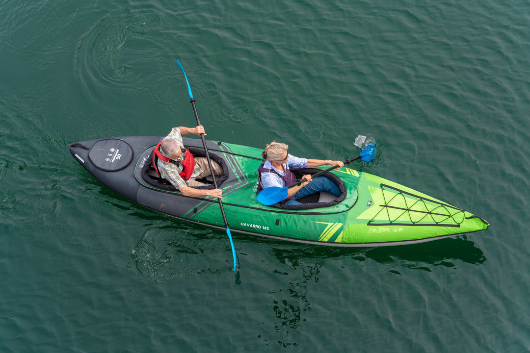 Two paddle in a Navarro 145 kayak on calm water, viewed from above.