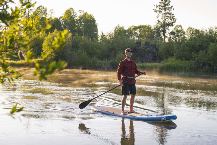 Enjoy the Cascade 10 Paddleboards lightweight glide on a calm river amid trees.