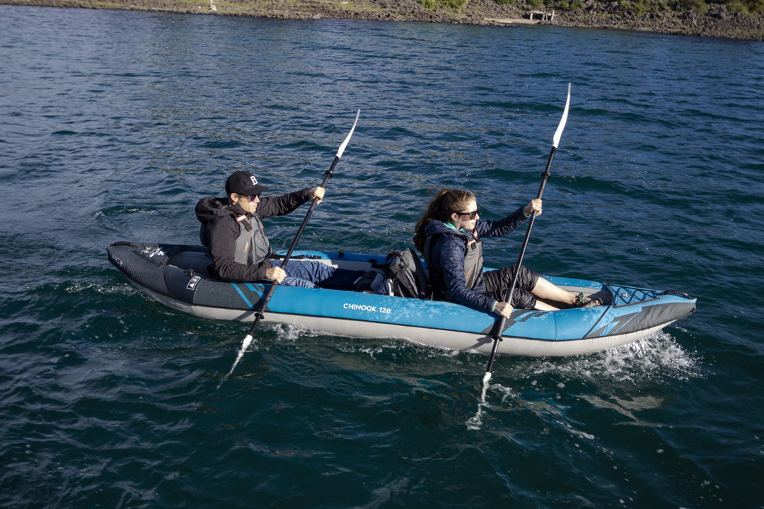 Two enjoy tandem paddling the Chinook 120 kayak on a sunny day in calm, open water.
