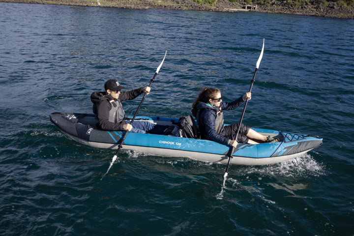 Two enjoy tandem paddling the Chinook 120 kayak on a sunny day in calm, open water.