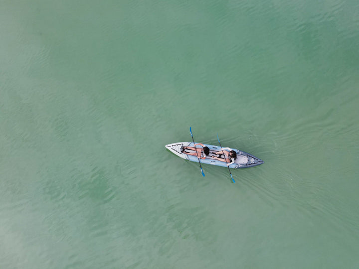 Aerial view of a Cirrus Ultralight 150 tandem kayak gliding on calm, greenish water.