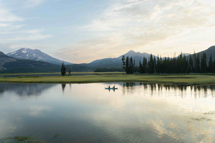 The Cirrus Ultralight 150 on a calm lake at sunrise, with mountains and trees in view.