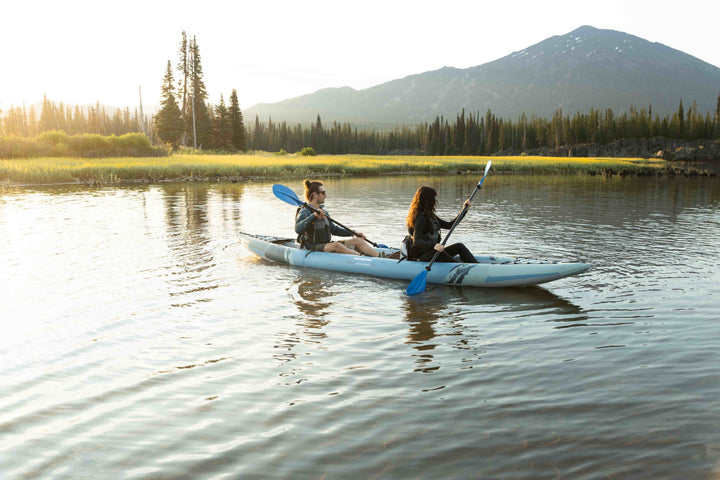 Two in a Cirrus Ultralight 150 kayak on a calm lake with mountains and trees.