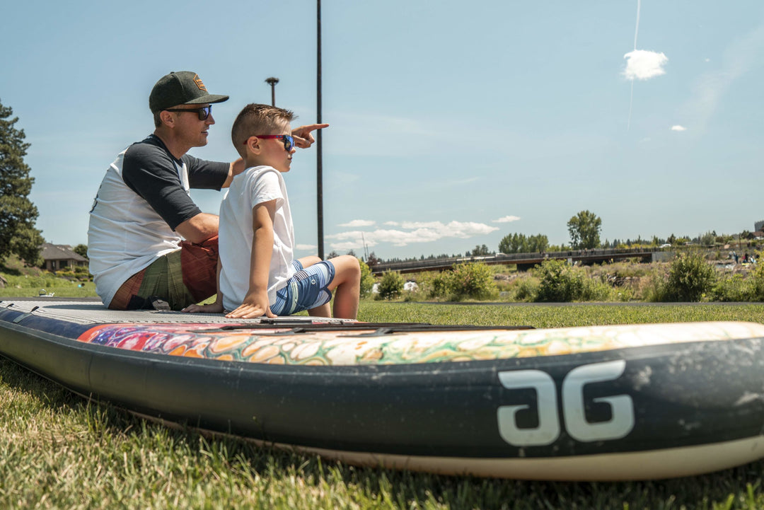 Two on the Kush 11 Paddleboard in a grassy area, one pointing forward.