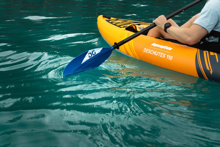 Kayaker on clear turquoise water with a bright orange Deschutes 110 kayak.